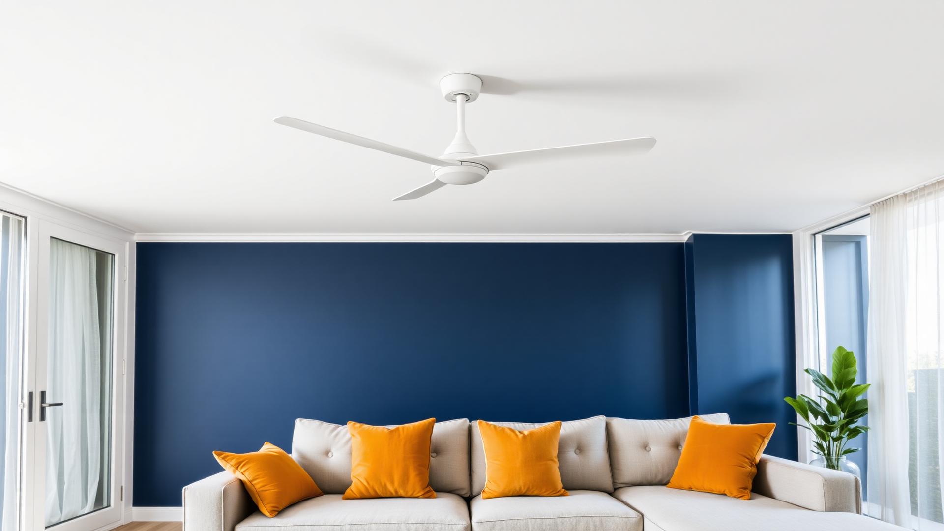 Modern white three blade ceiling fan installed on a white ceiling above a Sydney living room with a navy blue feature wall and amber cushions